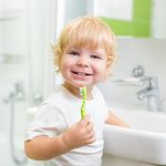 <wbr>Happy kid or child  brushing teeth in bathroom. <wbr>Dental hygiene.